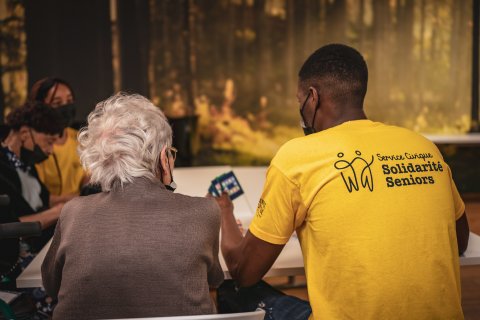 Volontaire et personne âgée de dos faisant une activité