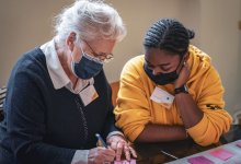 Jeune volontaire aidant une personne âgée pendant un atelier